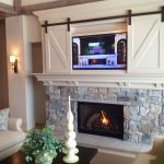 Stone fireplace with cabinet above for TV with barn doors